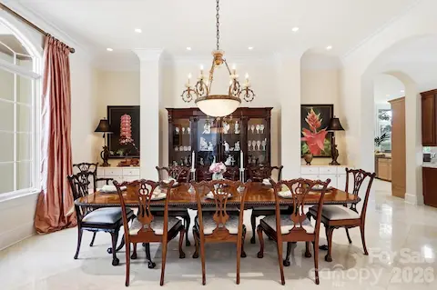 From the foyer, the home opens naturally into its main entertaining spaces, creating an inviting flow from one room to the next. A wide arched opening leads to the formal dining room, while the central hall continues toward the kitchen and great room beyond. Architectural columns, detailed millwork, the upper-level gallery, and the staircase’s rich wood treads and iron railings add character while preserving the home’s open, connected feel.