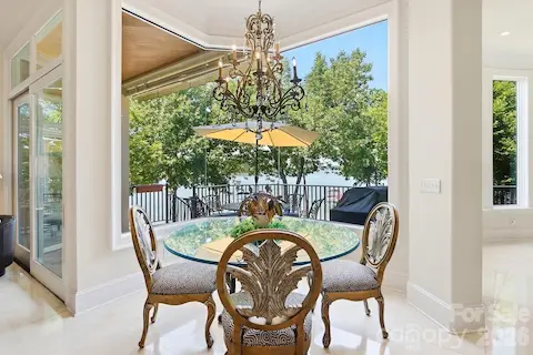 Just beyond the kitchen, the bright breakfast area offers a relaxed place to dine while enjoying expansive views toward Lake Norman through oversized windows. The open archway connects seamlessly to the two-story great room, creating an easy flow between casual dining, indoor gathering spaces, and the outdoor terrace beyond.