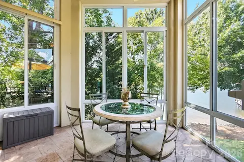 Continuing outdoors, the screened porch provides a peaceful retreat surrounded by mature trees and calming lake views. With room for casual dining and lounging, it offers a sheltered setting to enjoy the waterfront atmosphere throughout much of the year.