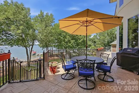 Stepping outside, the expansive terrace creates an inviting setting for outdoor dining and entertaining, with wrought-iron railings, shaded seating, and elevated views across Lake Norman toward the private dock.