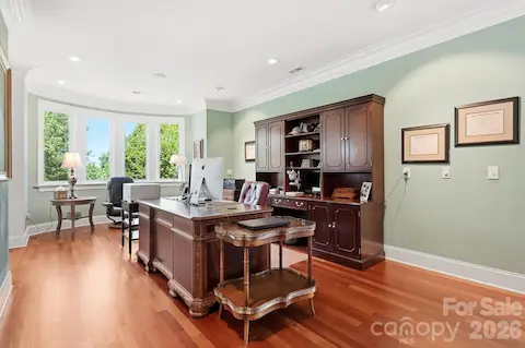 A spacious private office offers an elegant work-from-home setting with hardwood floors, extensive built-in cabinetry, recessed lighting, and a large walk-in storage closet conveniently located just behind the office, providing exceptional space for files, supplies, and additional household storage.