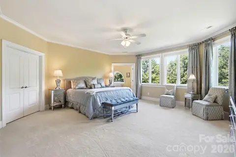 This generously sized upper-level bedroom offers a peaceful retreat with a broad wall of windows framing treetop and Lake Norman views. Soft carpeting, crown molding, and direct access to the adjoining bath complete the comfortable suite.
