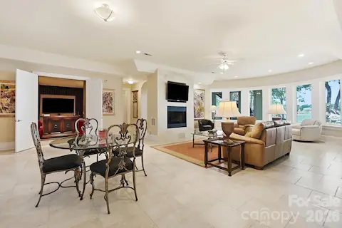 The lower-level entertaining area offers a relaxed gathering space with a fireplace, generous seating area, and a sweeping wall of windows. Its proximity to the wine cellar and other recreation spaces makes it ideal for casual entertaining.