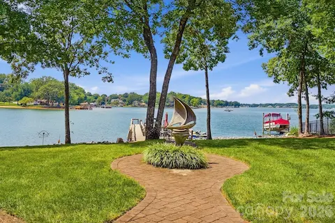 A beautifully manicured lawn and winding brick pathway create a graceful approach to the water, framed by mature shade trees and expansive Lake Norman views. The private dock sits just beyond, reinforcing the home’s seamless connection to its waterfront setting.