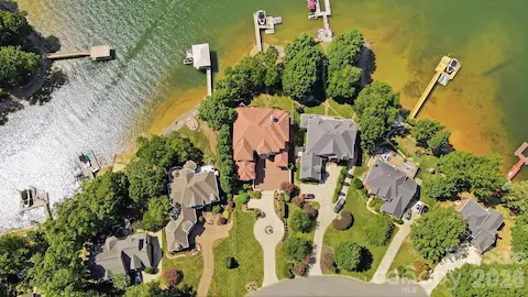 An aerial view highlights the home’s exceptional position on Lake Norman, with the residence centered on a beautifully landscaped waterfront lot and direct access to its private dock. The surrounding homes and shoreline setting emphasize the property’s desirable location within an established lakeside community.