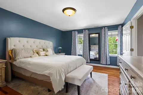 Large primary bedroom where hardwood floors continue & lots of natural light
