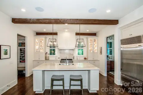 Kitchen features a large island with quatzite leathered countertop and upper glass door display cabinets with lighting