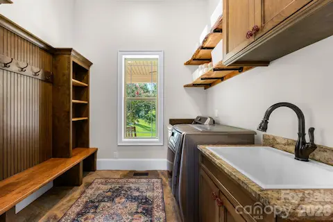 Mudroom -stone flooring, built in cabinets/shelving/bench, sink, and washer/dryer