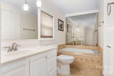 Bath off of the primary suite includes a ceramic tiled tub and a ceramic tiled walk in shower