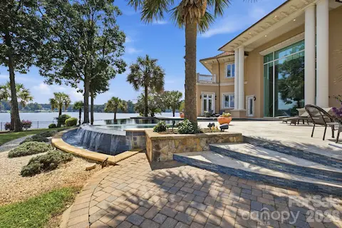 Stone terraces and steps connect the home seamlessly to the pool and waterfront grounds.