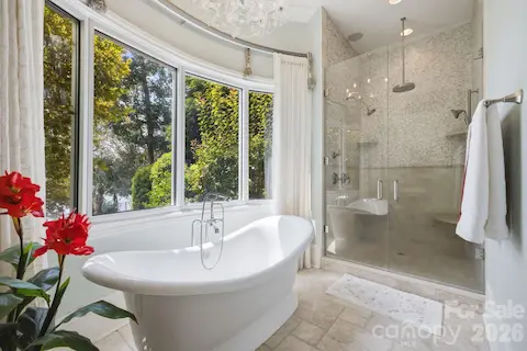 Spa-inspired primary bath features a freestanding soaking tub positioned beside oversized windows.