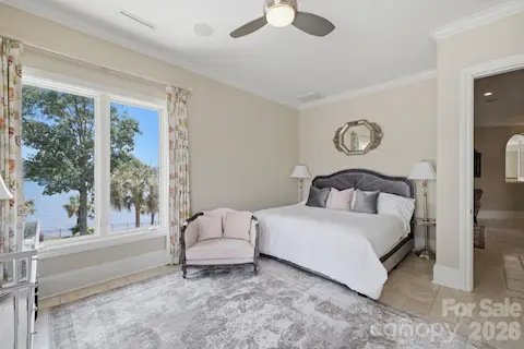 Spacious bedroom captures beautiful lake views through a wall of windows.