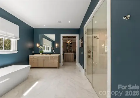 Primary bathroom with zero entry shower with multiple shower heads and bench seat.