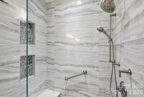 Thoughtful shower details include bench seating, handheld shower and built-in storage niches.