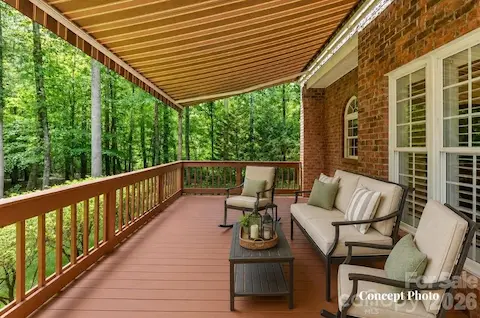 Concept photo of virtually staged covered deck featuring a retractable awning and serene views of the private, wooded backyard.