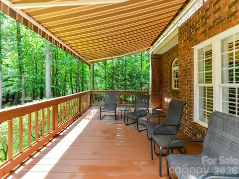 Enjoy peaceful outdoor living on the covered deck featuring a retractable awning and serene views of the private, wooded backyard.