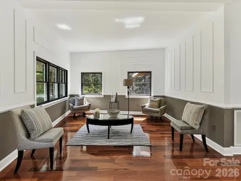 Spacious living or flex space features Brazilian hardwood floors, oversized windows, abundant natural light, and peaceful wooded views.