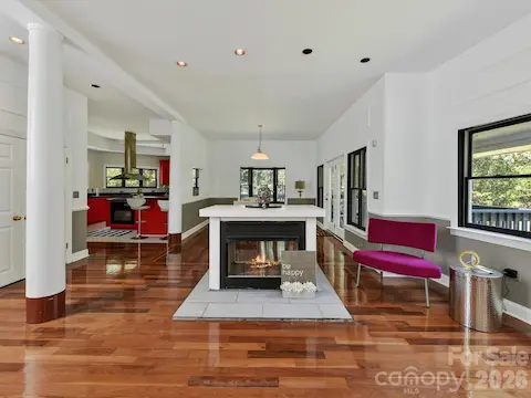 A centrally located fireplace anchors the open-concept living space, surrounded by Brazilian hardwood floors and easy flow into the kitchen and dining areas.