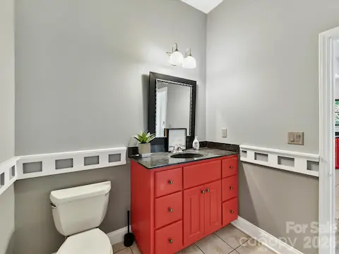 Convenient main-level powder room with tile flooring, ample vanity storage, and decorative trim details.