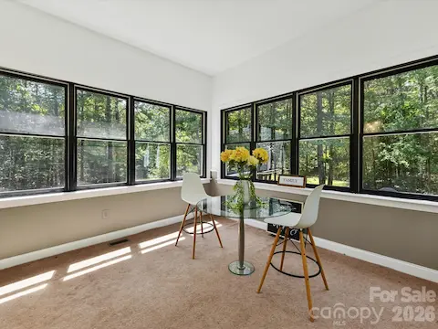 Light-filled sunroom surrounded by oversized windows showcases tranquil wooded views and the privacy of this expansive Davidson property.