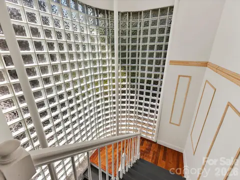 Dramatic curved floor-to-ceiling glass block wall floods the staircase with natural light, creating a distinctive architectural focal point.