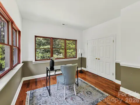 Versatile secondary bedroom with Brazilian hardwood floors, abundant windows, wooded views, and ample closet space is ideal for a bedroom or home office.