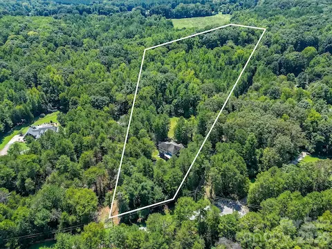 Aerial view showcases the home’s expansive wooded acreage, privacy, and impressive natural surroundings.