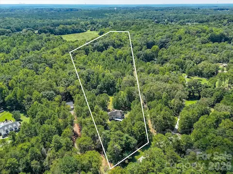 Elevated aerial view highlights the size and depth of the property, with the home tucked among mature trees and abundant green space.