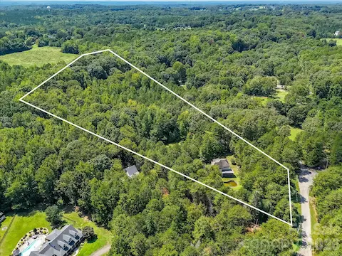 Sweeping aerial view showcases the property’s extensive wooded acreage and secluded setting, offering a rare sense of space and privacy.