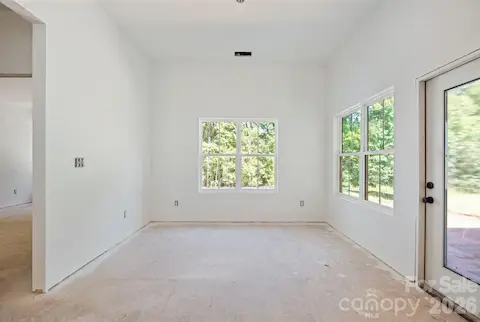 Large dining area overlooking the tree-lined backyard. To the right, the primary wing is tucked away for privacy.