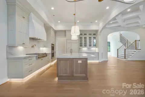 Side view of the kitchen highlighting seamlessly integrated panel-ready appliances, glass-front upper cabinetry, and refined custom finishes throughout.