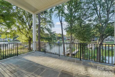 Main-level porch featuring soaring 12' tongue-and-groove ceilings, sleek steel railings, and beautiful water views.
