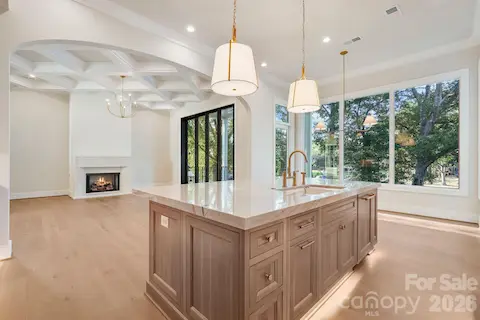 Open sightline from the kitchen into the family room, showcasing the seamless flow of the main level and abundant natural light from expansive windows.