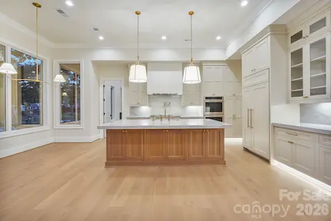 White oak island accented by two oversized pendant lights, intentionally positioned to preserve a clean sightline to the Venetian plaster hood.