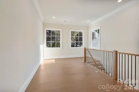 Upstairs gallery filled with natural light from expansive windows, creating an open, airy transition while capturing beautiful main-channel water views.
