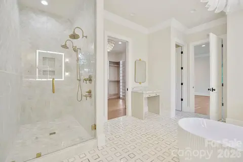 Luxurious marble shower featuring dual shower heads, floor-to-ceiling tile, and expansive frameless glass, complemented by a dedicated makeup vanity for a truly spa-inspired primary bath.