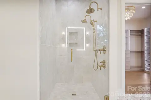Showstopping marble shower featuring dual shower heads, floor-to-ceiling tile, and expansive frameless glass, creating a luxurious spa-like experience within the primary suite.