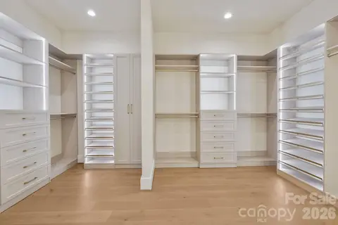 Custom-designed primary closet featuring integrated LED-lit shelving, extensive built-in storage, and a refined boutique-inspired feel.