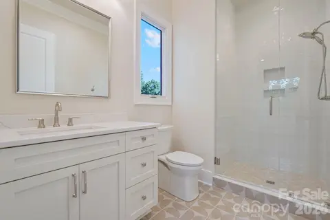 Bedroom 2 ensuite bath features floor-to-ceiling tile and a thoughtfully placed window that fills the space with natural light, creating a bright, elevated finish.
