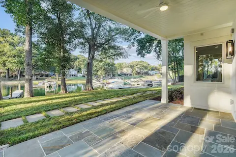 Covered basement porch featuring flagstone flooring and a tongue-and-groove ceiling for an elevated outdoor living space.