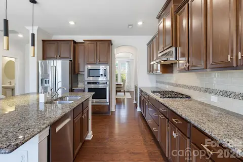 The kitchen offers abundant cabinetry, granite work surfaces, and stainless appliances, with a layout designed for comfortable everyday cooking