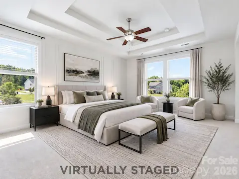 Virtually staged, the spacious primary bedroom becomes a serene retreat with room for a full furniture suite and a sunny sitting area.