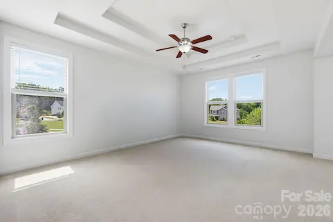 The oversized primary bedroom features a tray ceiling, multiple windows, and the peaceful scale of a true private retreat.