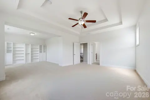 The primary suite extends into a generous lounge with custom built-in shelving, offering room to unwind beyond the sleeping area