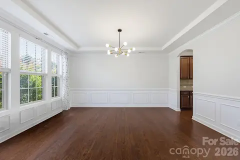 The formal dining room pairs tray-ceiling detail and classic wainscoting with generous windows for a bright, polished setting.