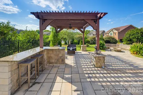 The pergola and outdoor kitchen area set the stage for shaded afternoons, casual dinners, and relaxed evenings outside.