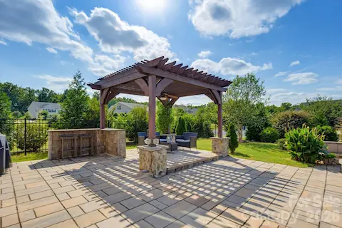 A wide patio view shows the pergola, built-in serving area, and open space for hosting family and friends.