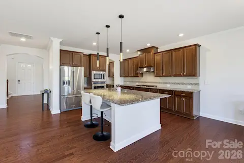 A broad view of the kitchen highlights the central island, updated pendant lighting, and generous storage that keep your life organized