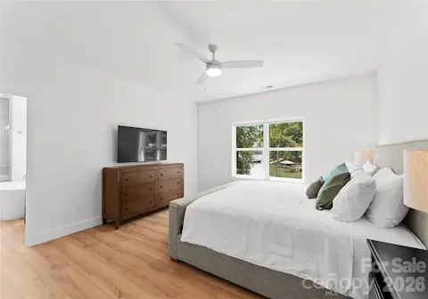 Wake to glimpses of the lake through the trees in this bright, spacious primary bedroom, finished with warm wood floors.