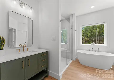 A sage-toned vanity and brass accents bring a refined touch to this bathroom, which connects directly to the adjoining bedroom.